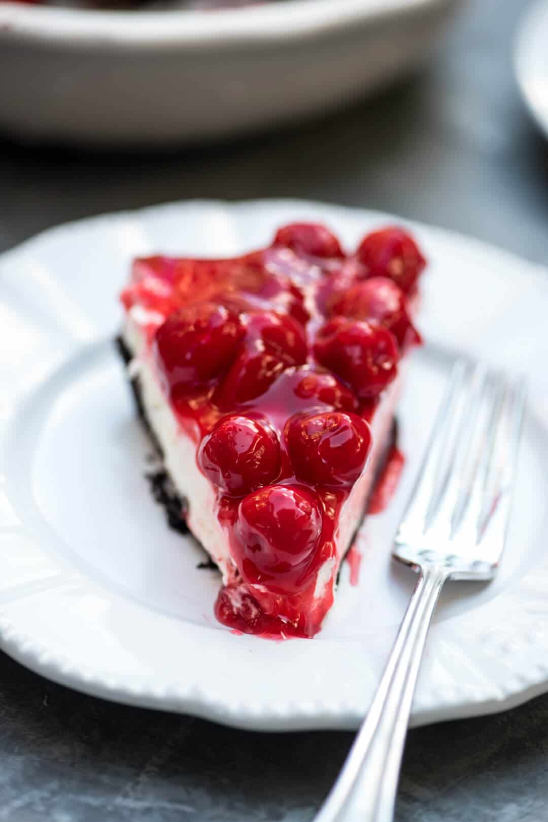 A slice of Cherry Cheesecake Pie on a white plate with a fork.