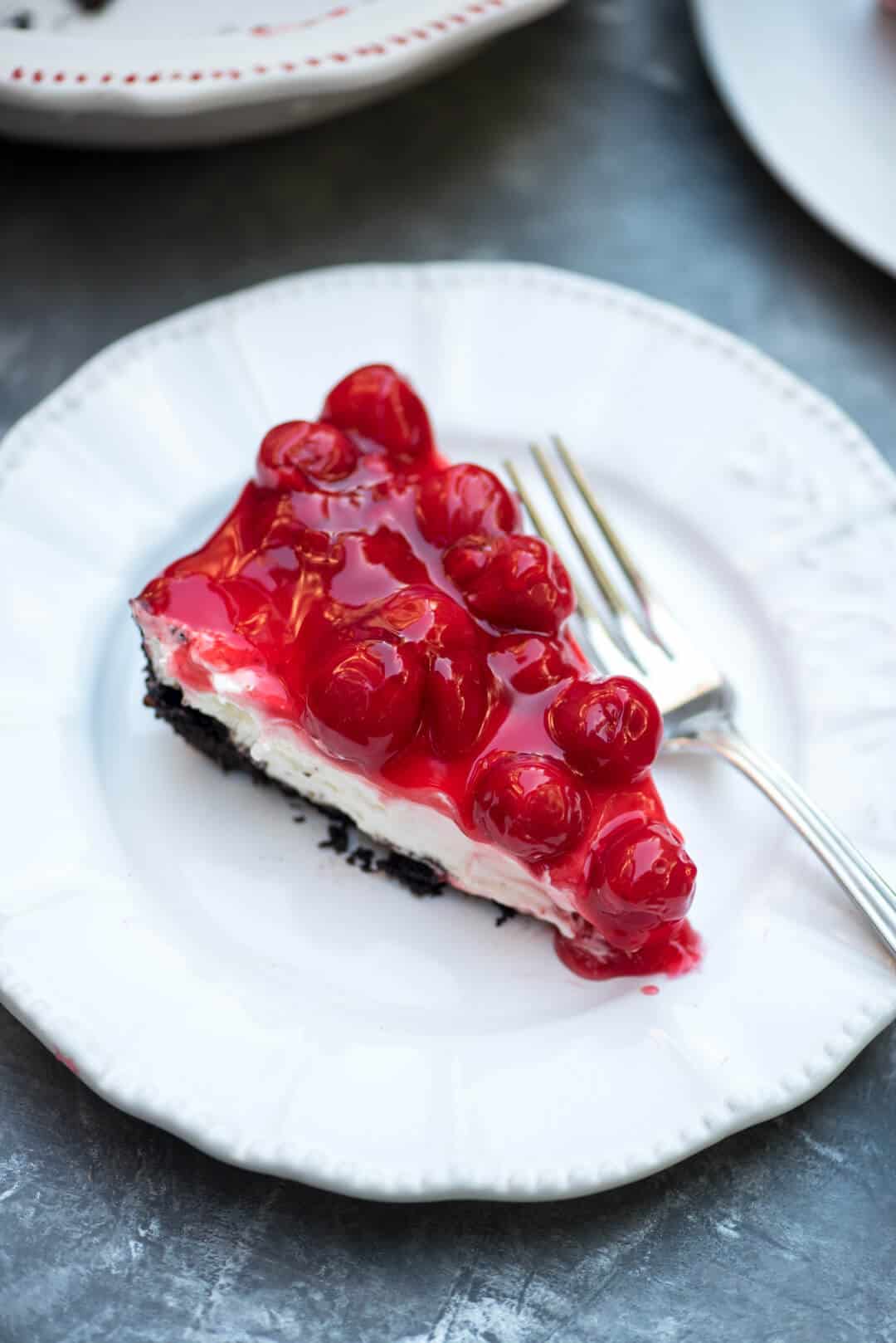 A slice of Easy Cherry Cheesecake Pie on a white plate with a fork.