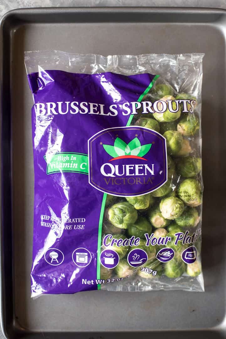 A bag of brussels sprouts on top of a baking sheet.