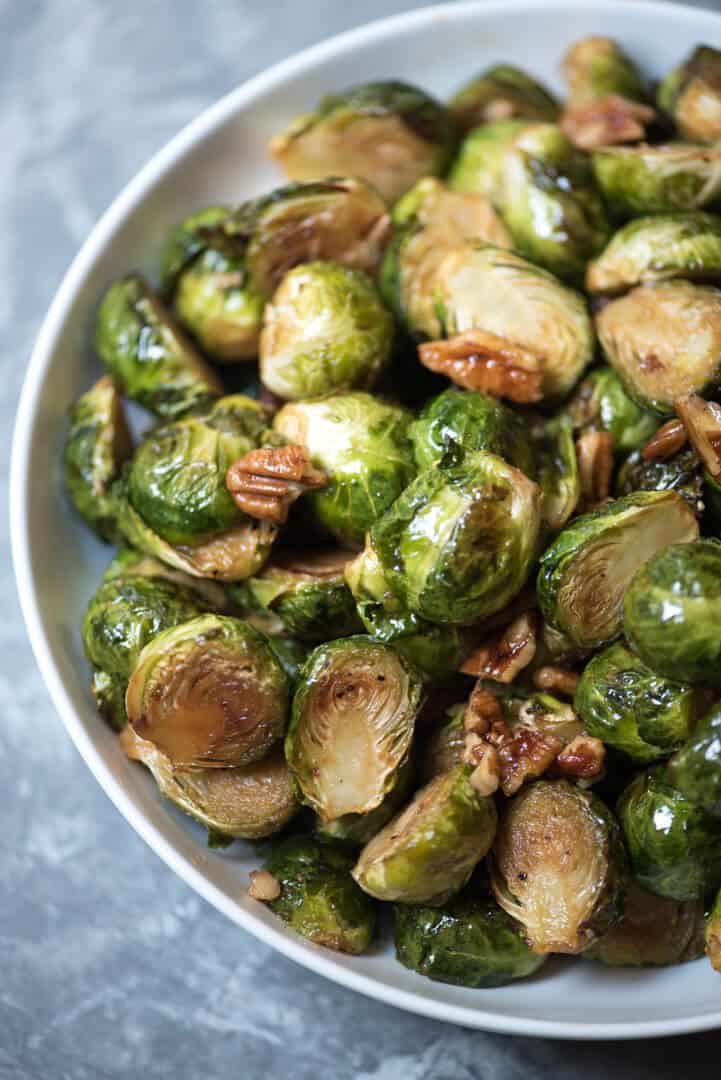 A closeup of roasted brussels sprouts in a white bowl.