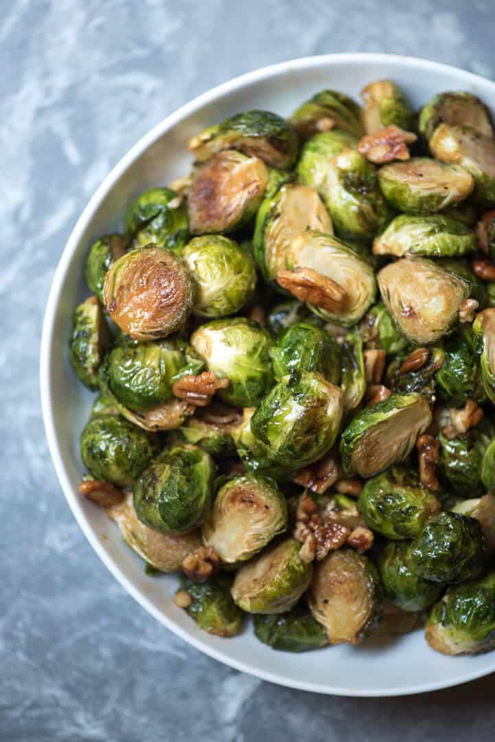 Brussels sprouts with pecans in a white bowl.