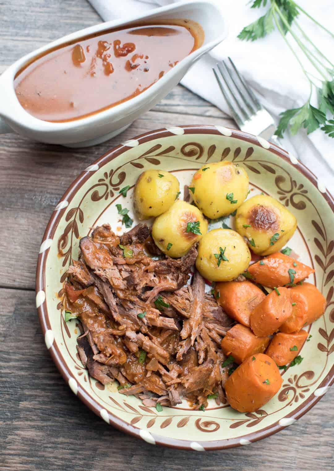 A serving of Slow Cooker Italian Pot Roast in a bowl with carrots and potatoes.