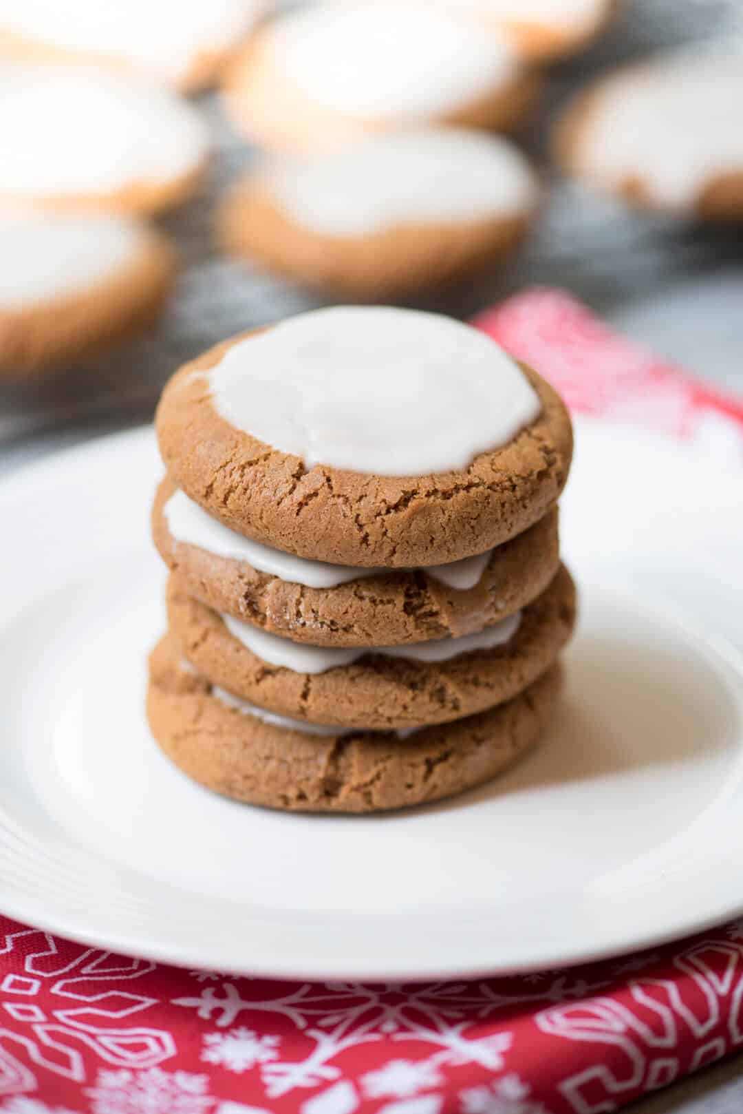 A stacked of iced molasses cookies on a white plate.