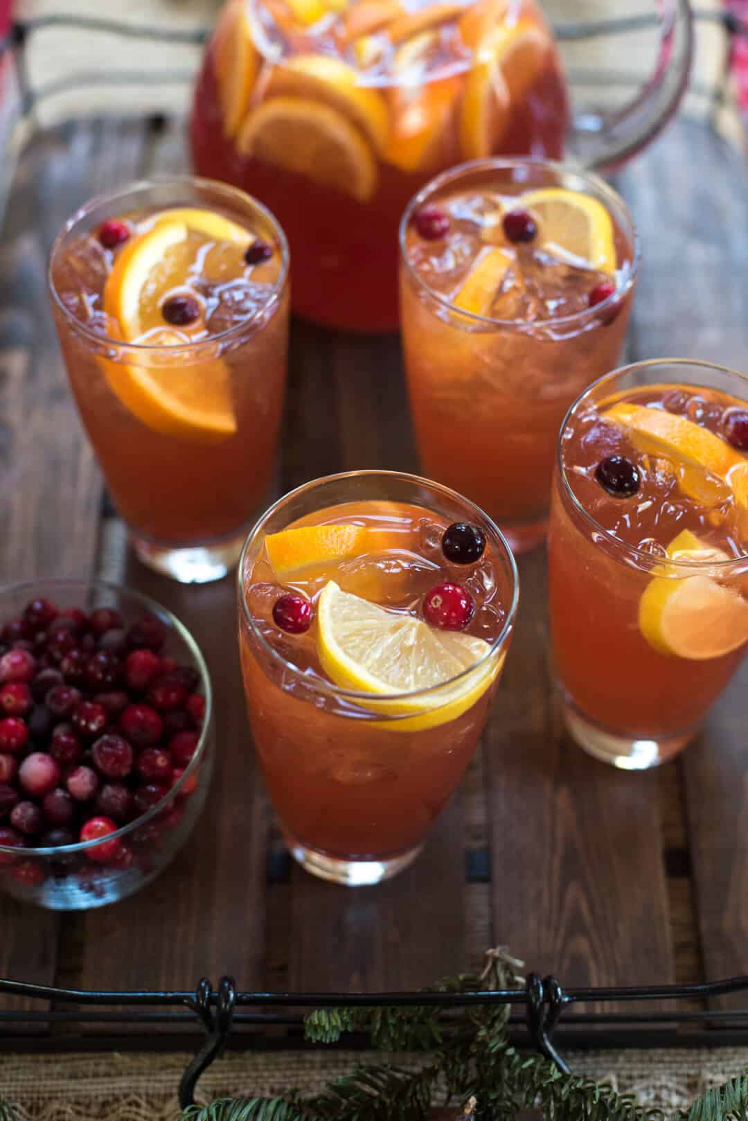 An over the top shot of glasses of iced tea garnished with lemon slices and cranberries.