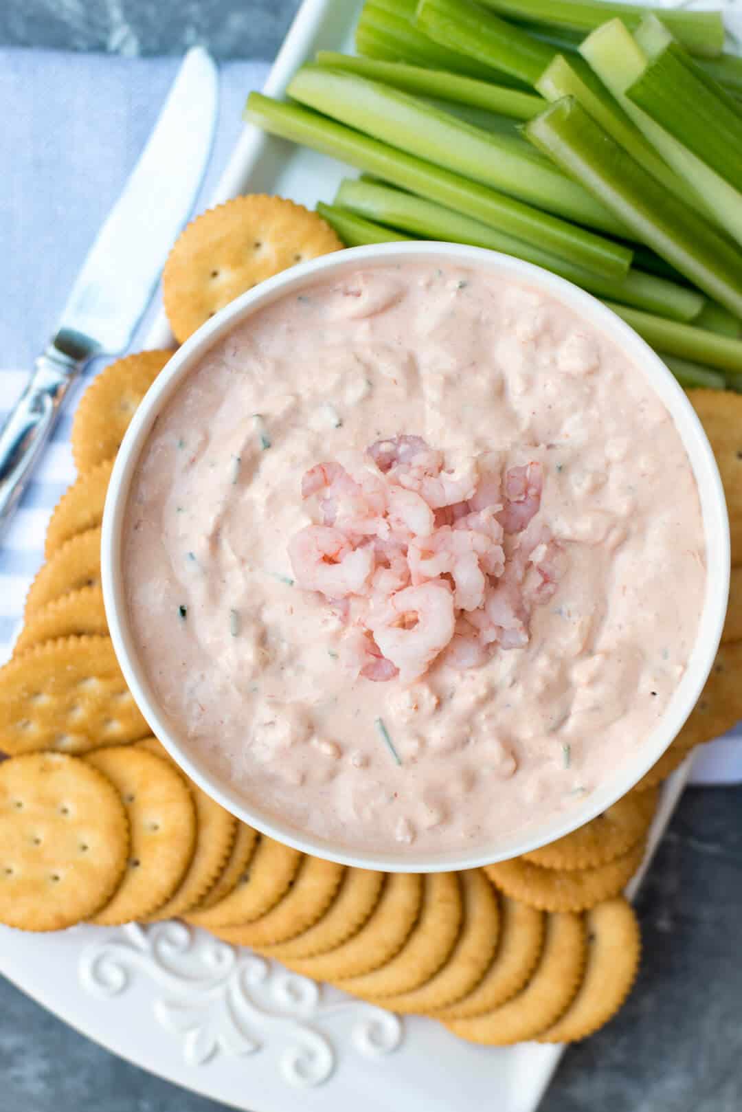 An over the top shot of Shrimp Dip on a platter with Ritz Crackers and celery sticks.
