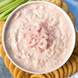 Shrimp Dip in a white bowl with ritz crackers and celery around it.
