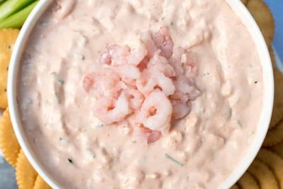 Shrimp Dip in a white bowl with ritz crackers and celery around it.