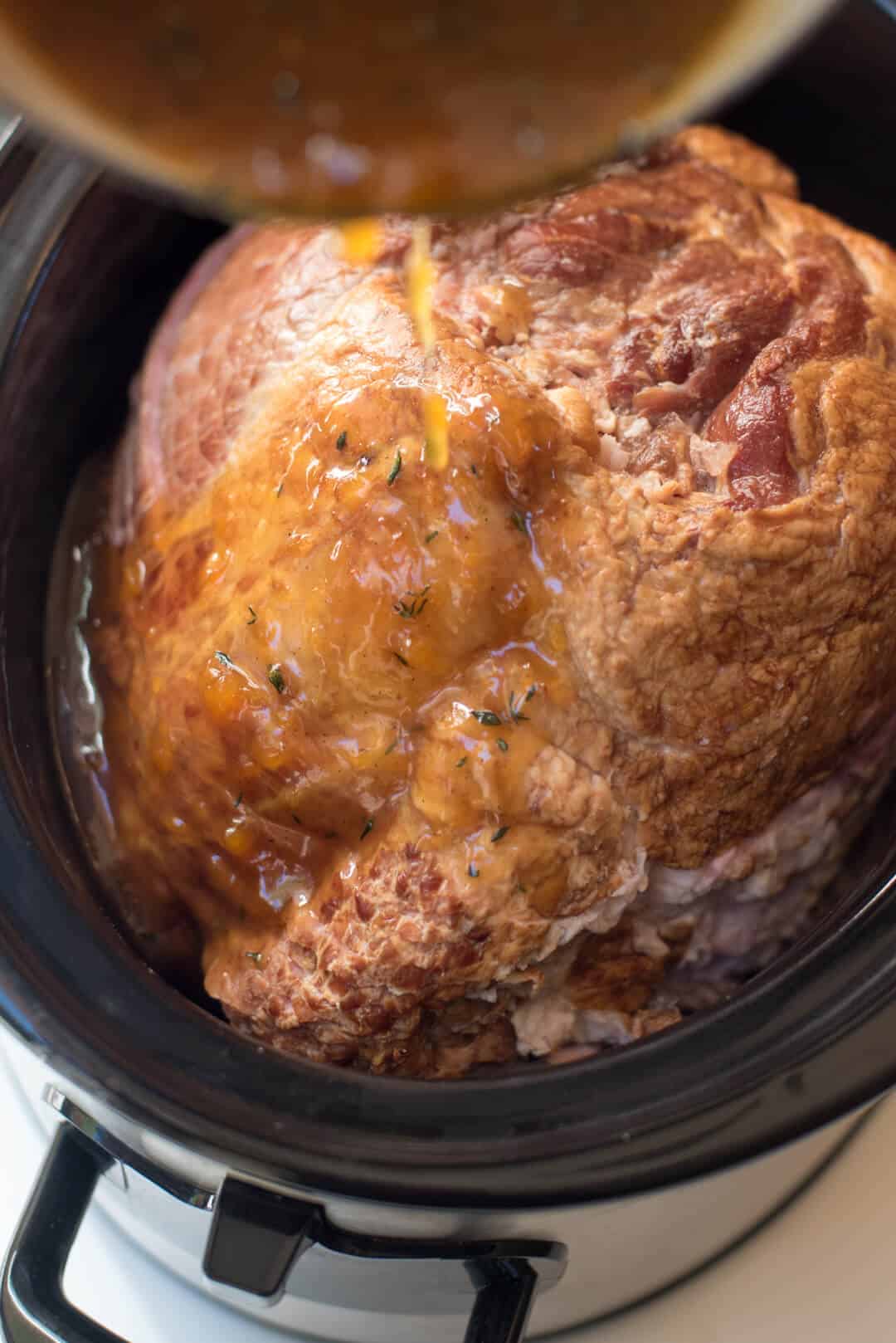 Pouring the Peach Thyme Glaze over the spiral sliced ham in the slow cooker.
