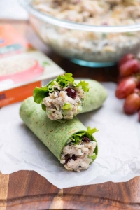 Chicken salad in a green wrap stacked on parchment paper.