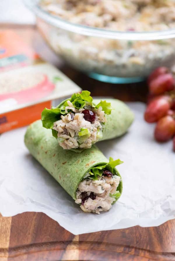 Chicken salad in a green wrap stacked on parchment paper.