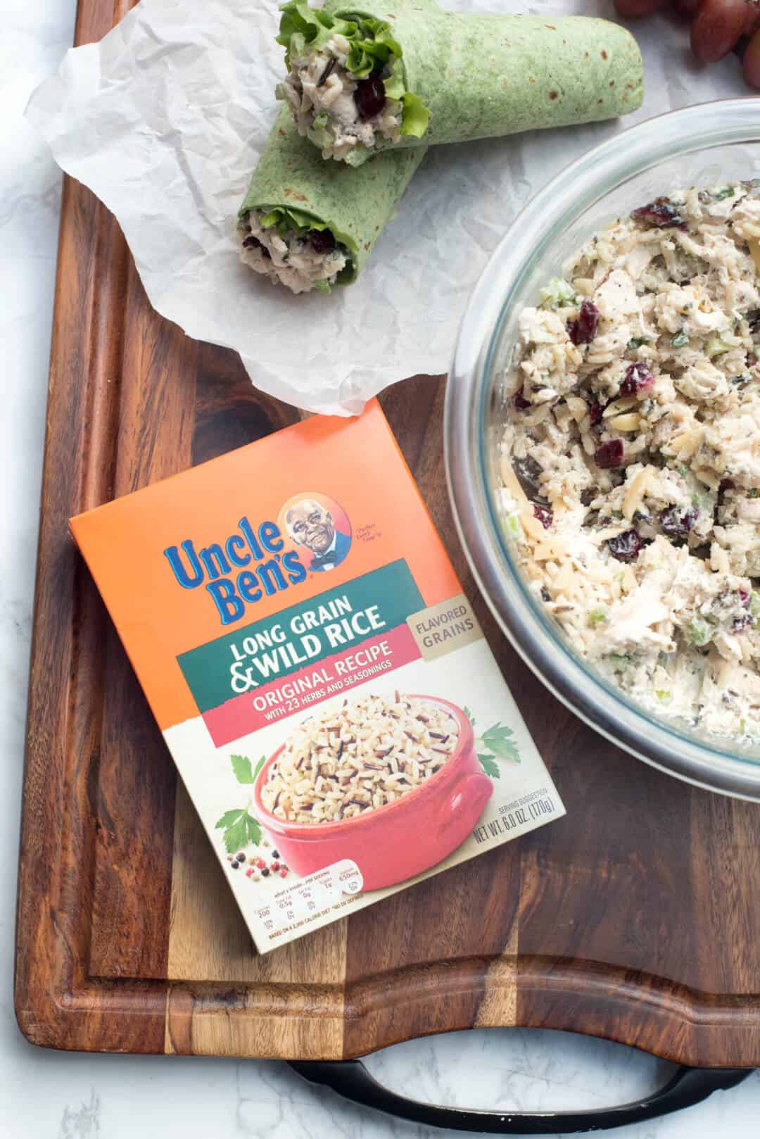 A wrap next to a bowl of chicken salad and a box of Uncle Ben's Long Grain and Wild Rice.