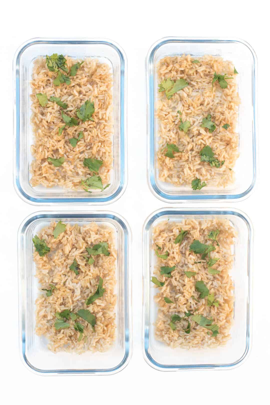 Brown rice and cilantro in four meal prep containers.