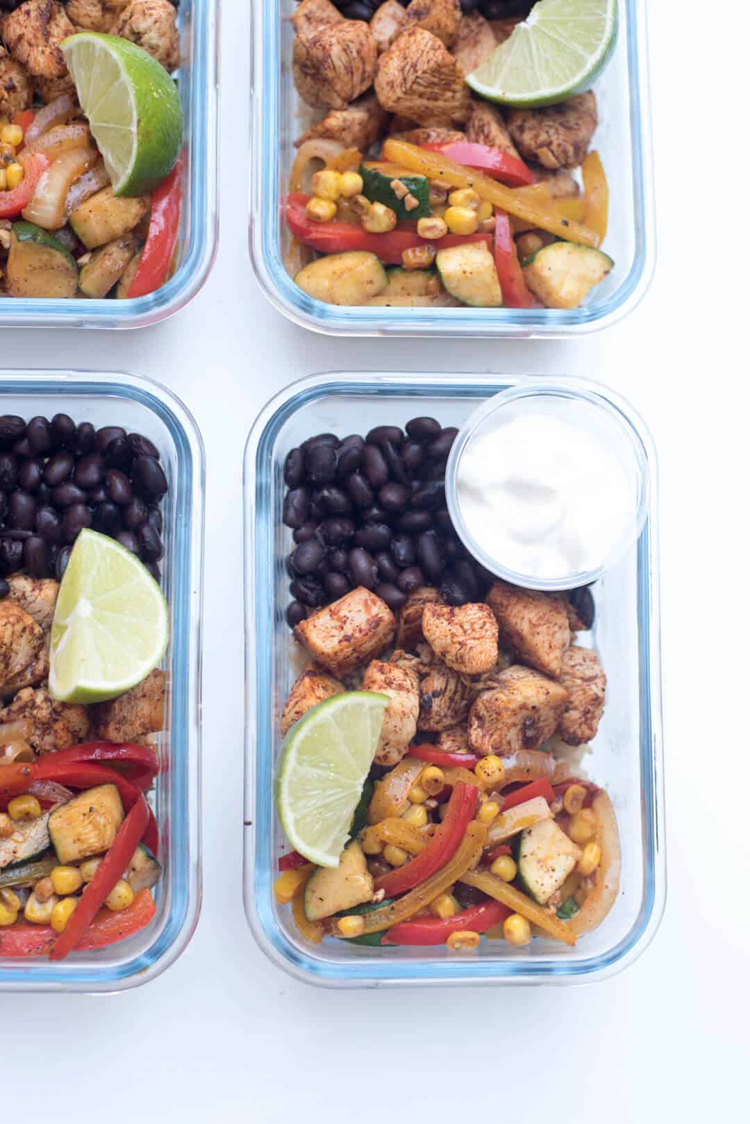 A small container of sour cream and a lime wedge on top of a Tex-Mex Chicken Meal Prep Bowl.