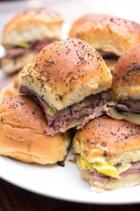 A close up of Italian Roast Beef Sliders stacked on a white plate.