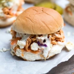 A close up of a chicken slider with blue cheese on a small bun.