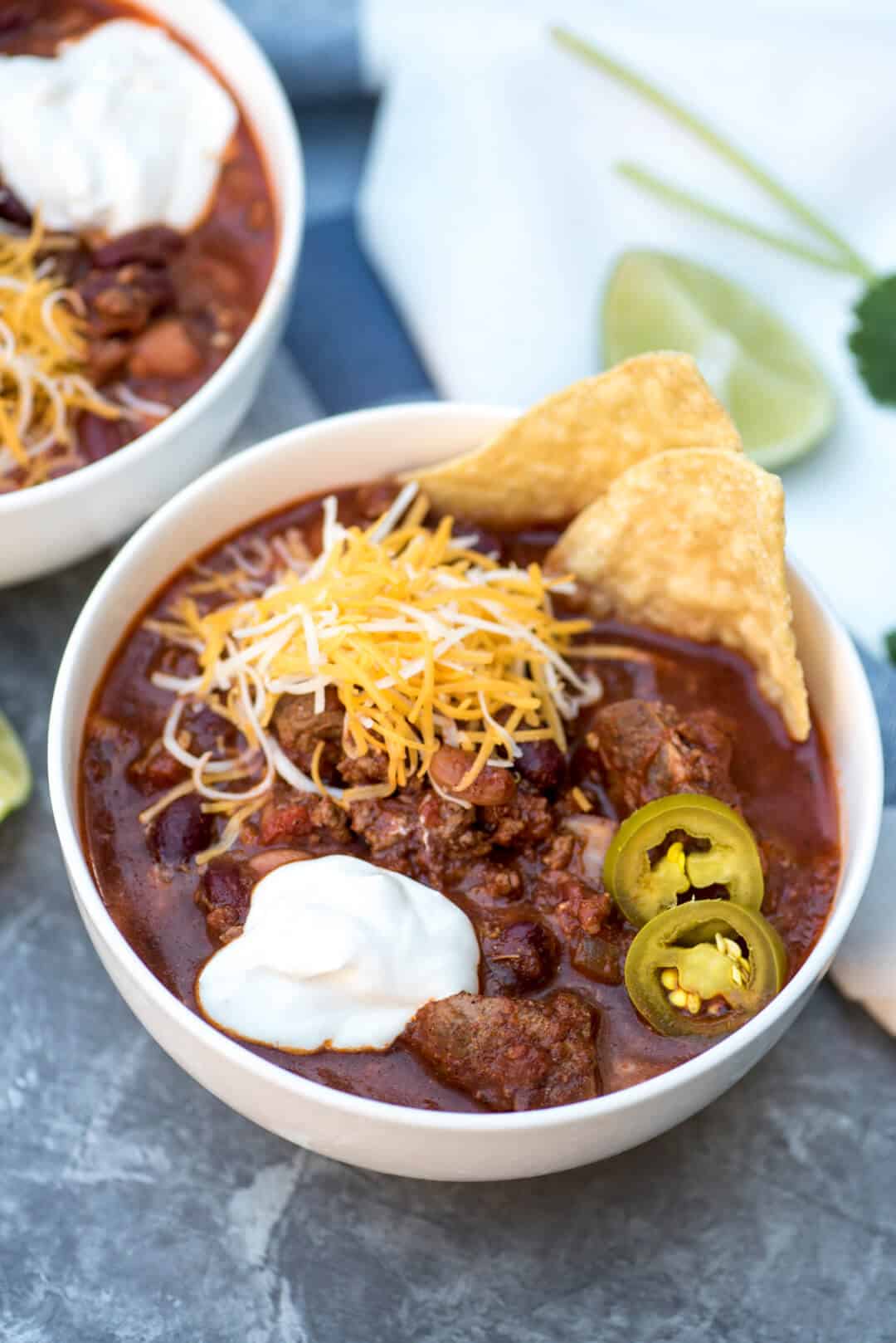 Slow Cooker Double Beef and Bean Chili in a white bowl topped with cheese and sour cream.