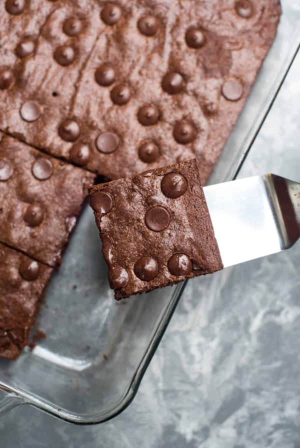A spatula lifts a brownie from a baking dish.