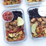 Glass meal prep containers filled with chicken, veggies, and black beans.