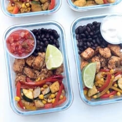 Glass meal prep containers filled with chicken, veggies, and black beans.