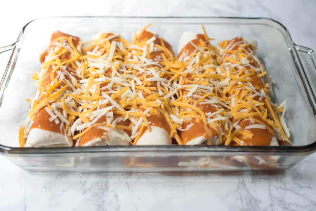 Turkey Black Bean Enchilada in a baking dish topped with enchilada sauce and cheese.