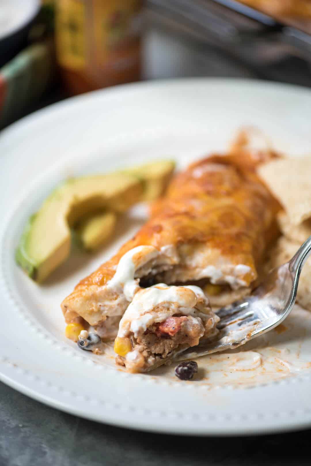 A fork pulling away a bite of enchilada.