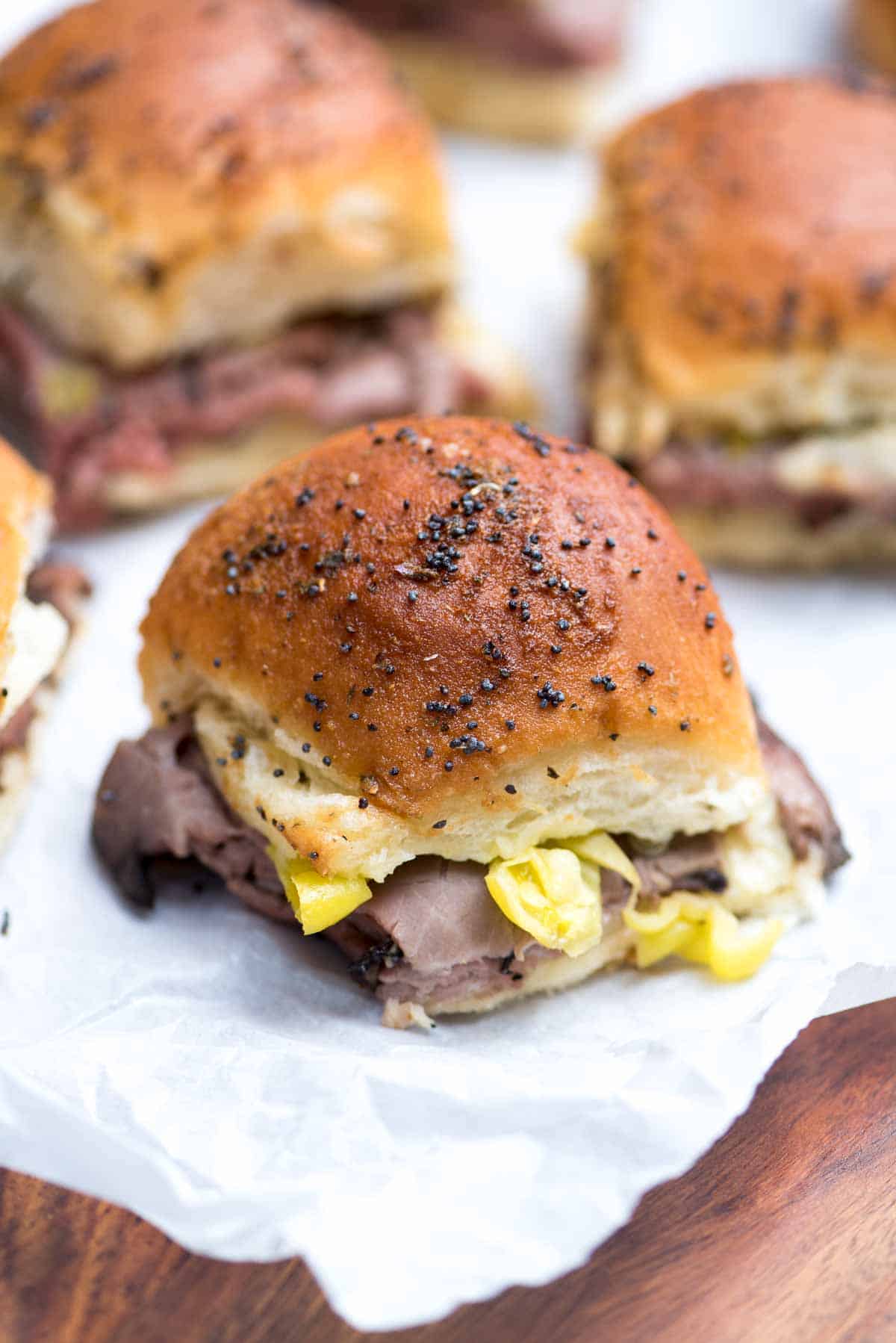 Italian roast beef sliders on a sheet of parchment paper.