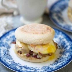 A breakfast sandwich on an English muffin on a blue and white plate.