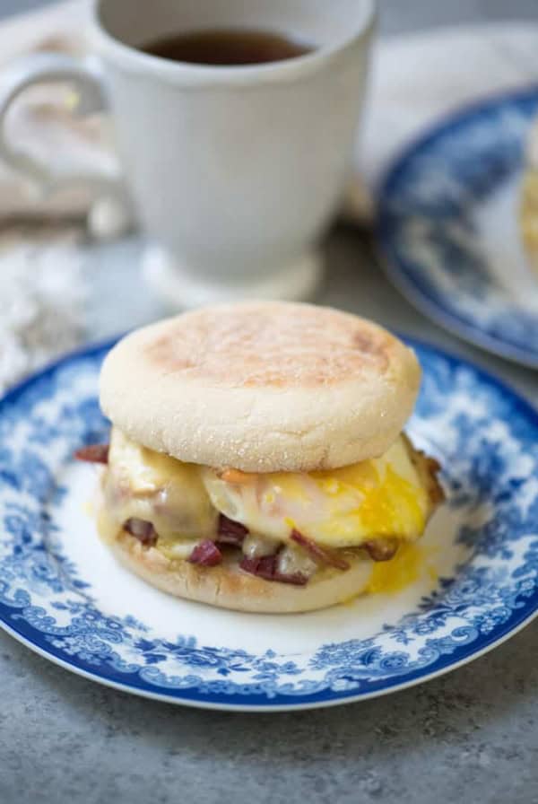 A breakfast sandwich on an English muffin on a blue and white plate.
