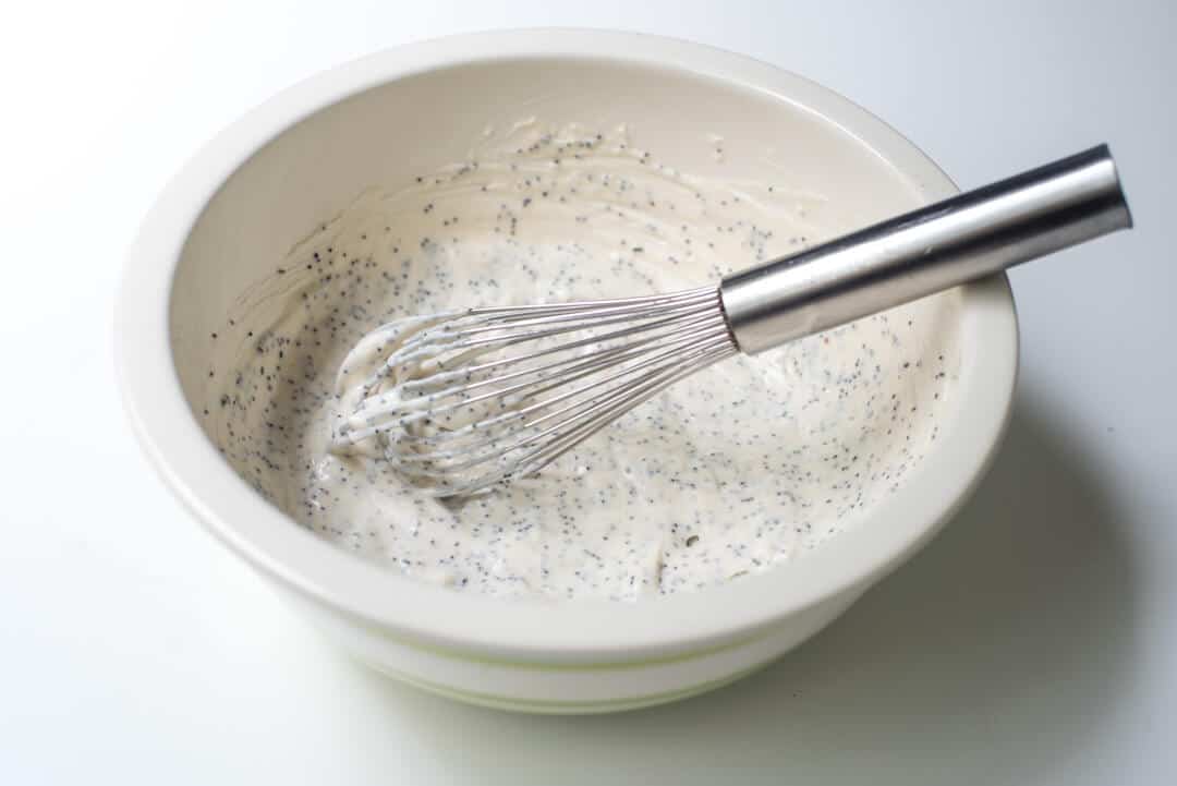 Poppy seed dressing in a white bowl with a whisk.
