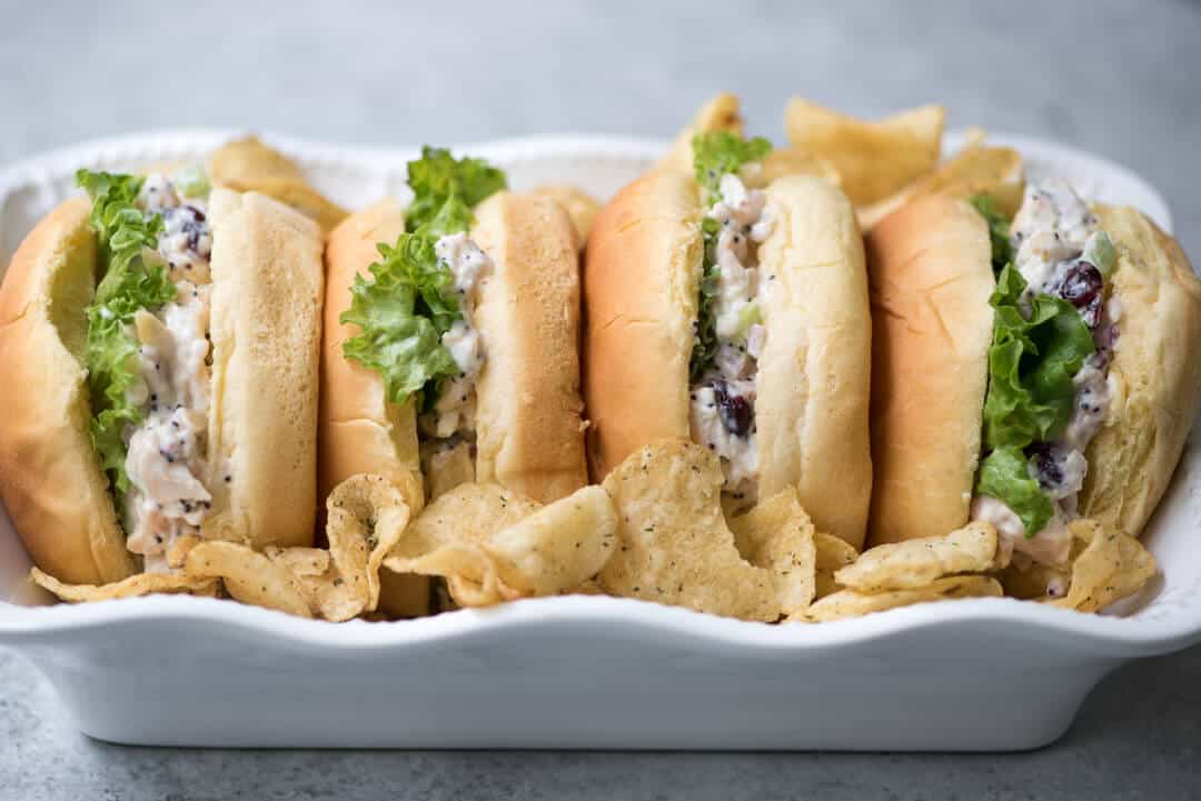 Cranberry Almond Poppy Seed Chicken Salad Sandwiches in a white serving dish with potato chips.