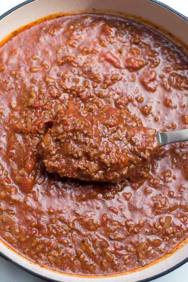 A spoon lifts Easy Homemade Spaghetti Sauce from a pot.