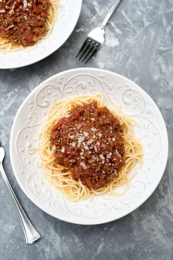 An over the top image of two white bowls filled with spaghetti and meat sauce.