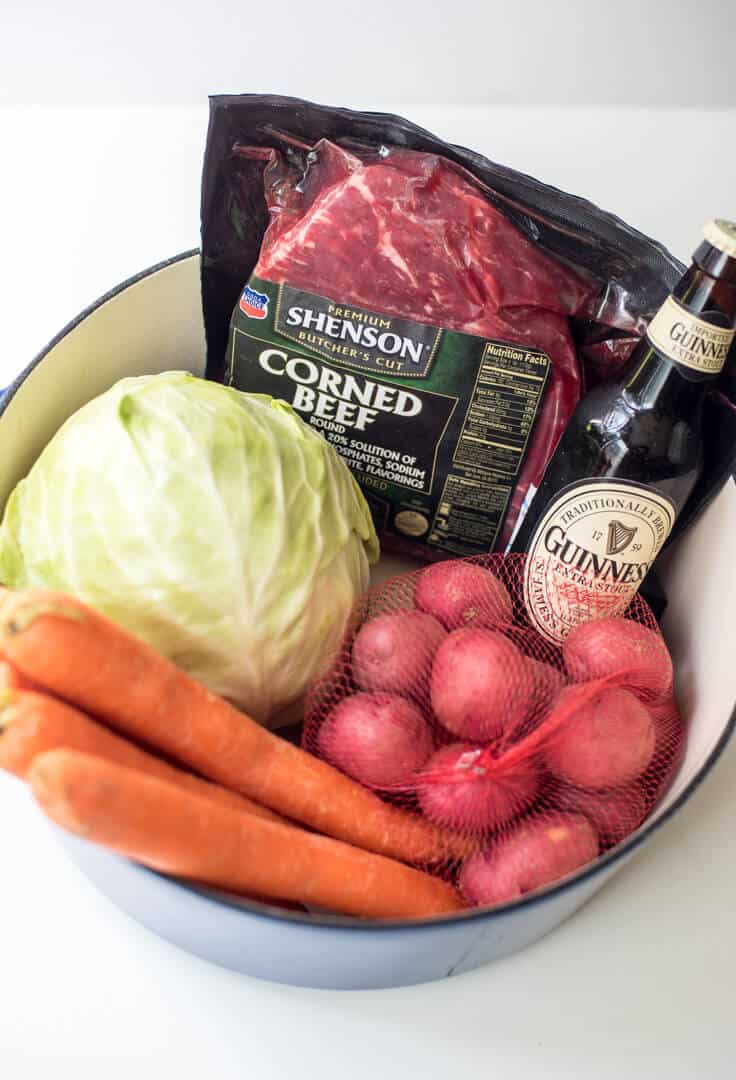 Shenson Corned Beef, a bottle of Guinness, red potatoes, carrots, and a head of cabbage.