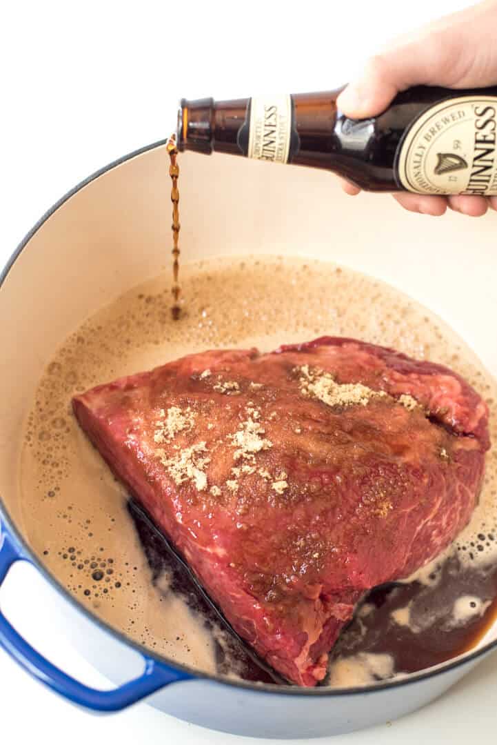 Guinness is poured over the corned beef in the Dutch oven.
