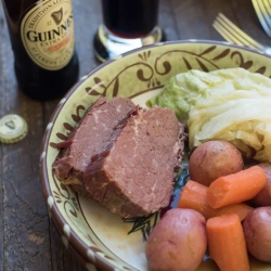 A bowl filled with corned beef and cabbage next to a bottle of Guinness.