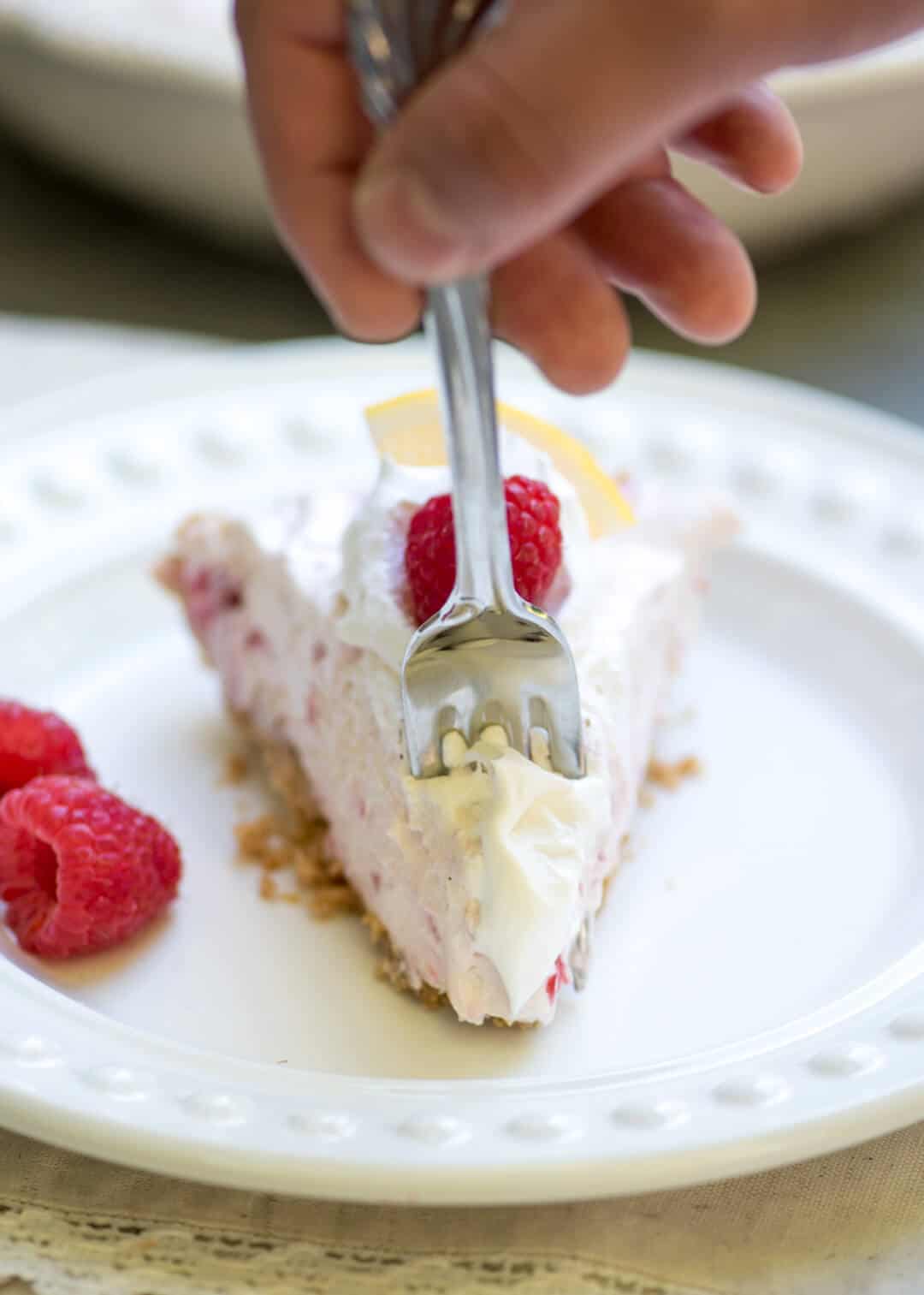 A fork digs in to a slice of Lemon Raspberry Pie.