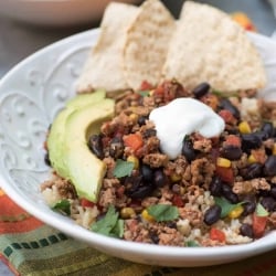 A bowl filled with turkey taco filling topped with sour cream and avocado.