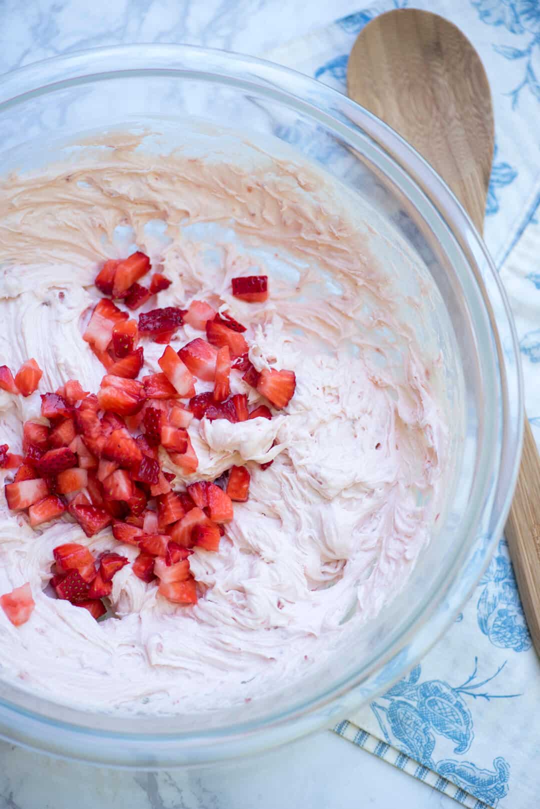 Strawberry buttercream with chopped fresh strawberries in a glass bowl.