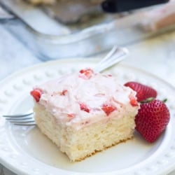 A close up of a slice of 7up sheet cake with strawberry frosting on a plate.