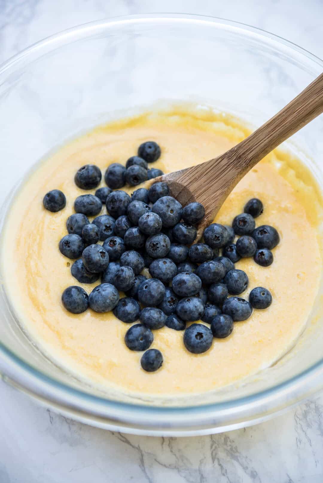 A bowl of muffin batter with fresh blueberries piled on top.