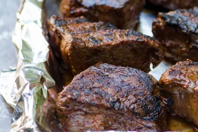 Grilled steak on a foil lined baking sheet.