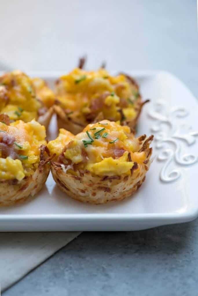 A close up of hash brown egg cups on a white platter.