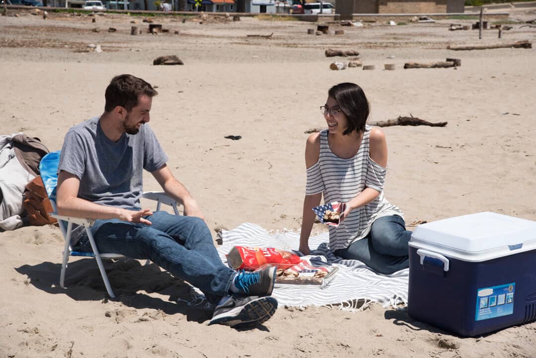 A young man and woman at the beach laughing and talking.