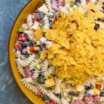 A bowl of pasta salad topped with crushed Doritos.