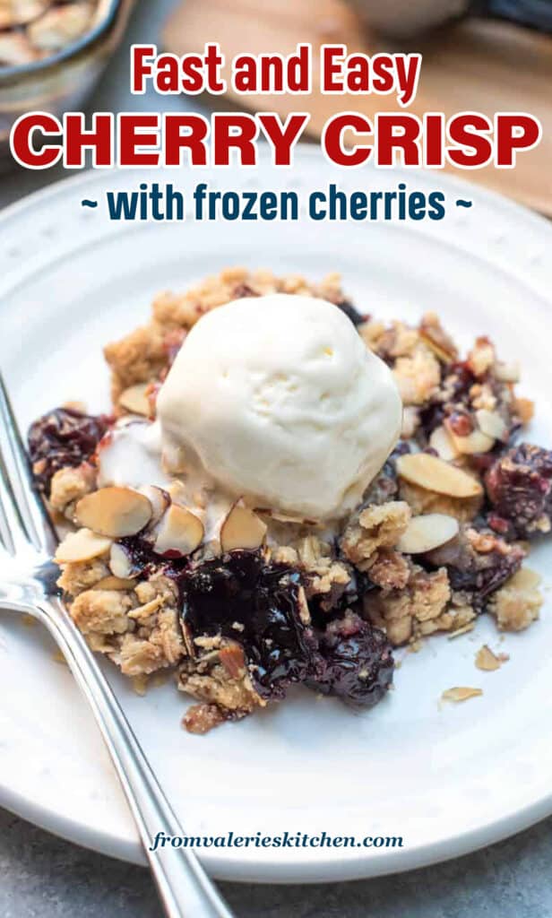 Cherry crisp topped with vanilla ice cream on a white plate with a fork with text overlay.