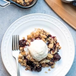 Cherry Crisp topped with vanilla ice cream on a white plate.