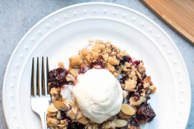 Cherry Crisp topped with vanilla ice cream on a white plate.