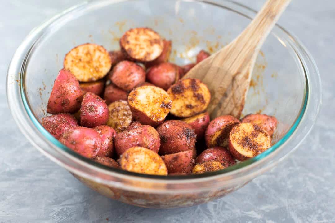 The potatoes are stirred to coat them with oil and spices.