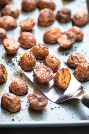 Spiced roasted potatoes on a baking sheet with a spatula.