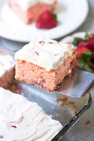 A piece of strawberry cake is lifted with a spatula.